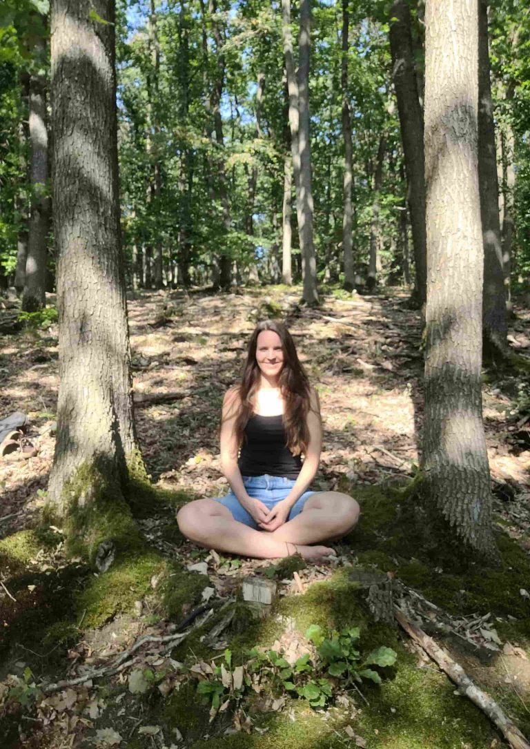 Frau sitzt entspannt und meditierend im Wald