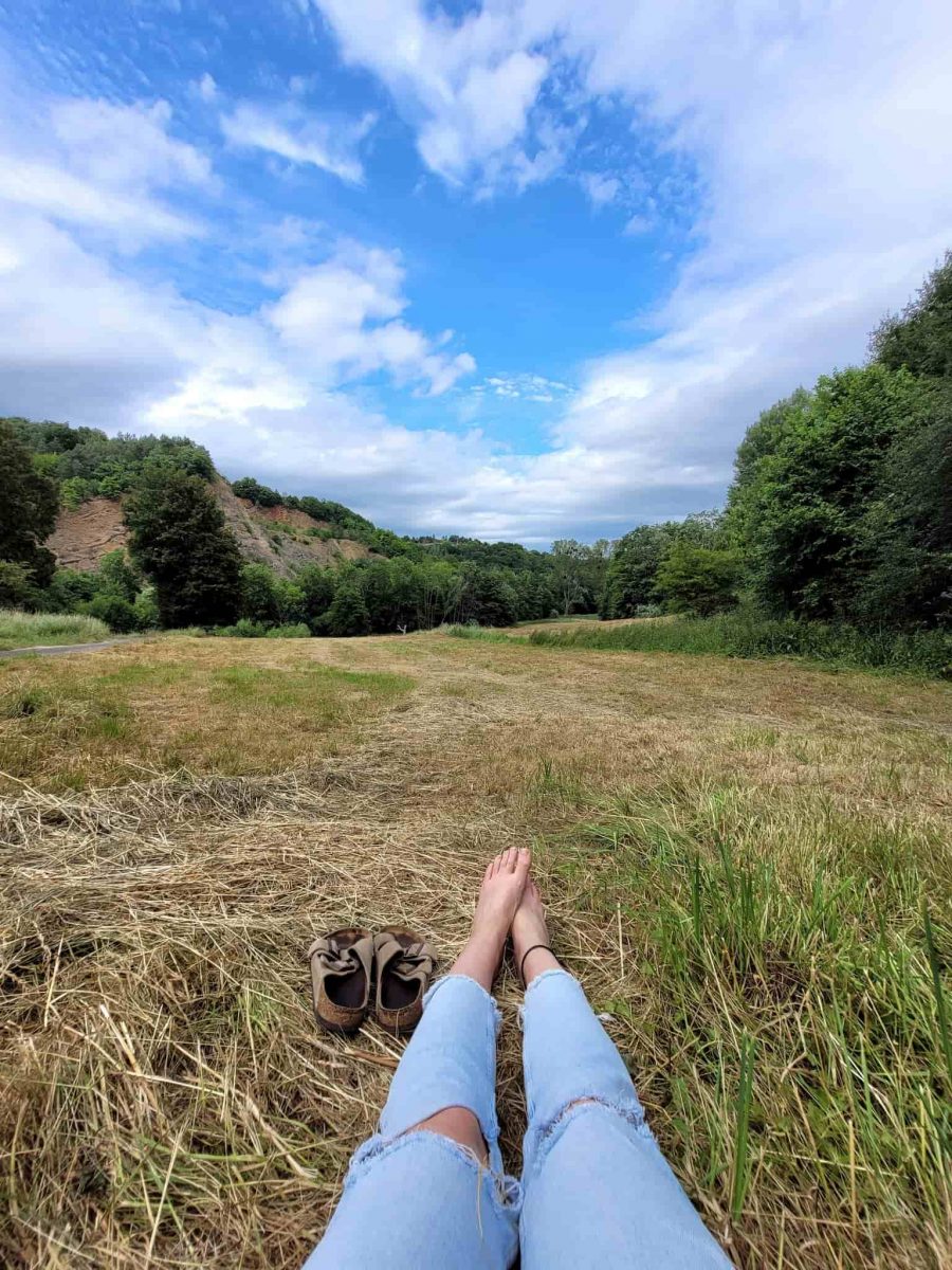 Frau sitzt entspannt in der Natur mit Blick auf den blauen Himmel